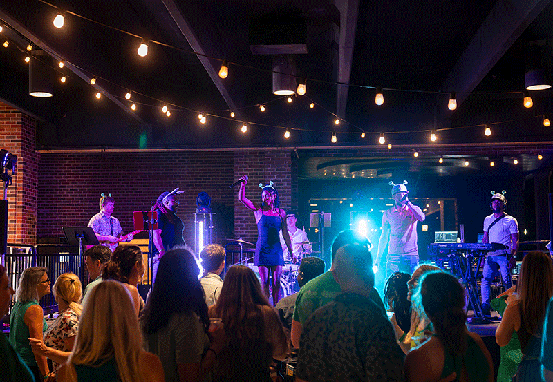 People dance under bright lights as a band plays.