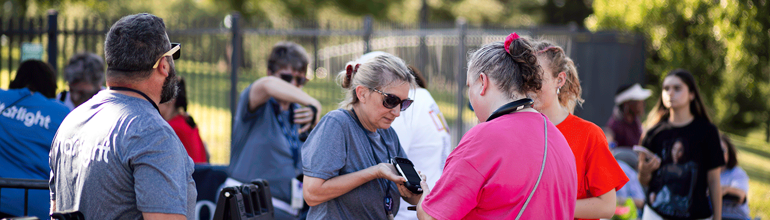 A woman with gray hair scans a ticket at the Starlight entrance for a women with brown hair wearing a bright pink shirt.