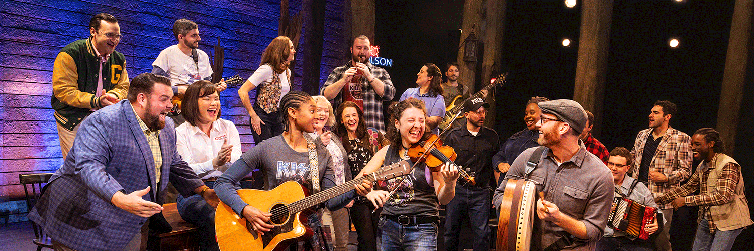 A diverse group of men and women play instruments, sing, and laugh.