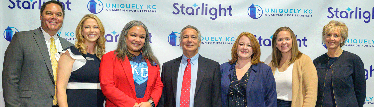 Amy Guerich stand with other board members in front of a Starlight sponsor screen.